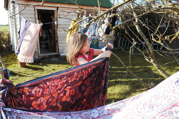 Young girl makes a den in the garden. Somerset, UK